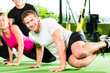 Photo: People in sport gym on suspension trainer People in sport gym on suspension trainer