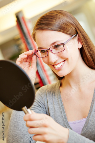 Photo: Frau mit Brille schaut in Spiegel Frau mit Brille schaut in Spiegel