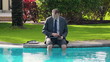 Video: Businessman sitting by the poolside and working on tablet comput Businessman sitting by the poolside and working on tablet comput