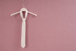 A white necktie is on lilac background.