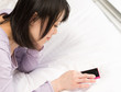 うつ伏せでスマートフォンを使う女性