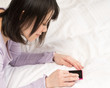 うつ伏せでスマートフォンを使う女性