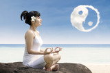 Beautiful girl exercise yoga  at beach under ying yang cloud