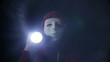 Scary masked man with torch light in darkness