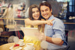 Happy young woman pointing something while sitting in cafe