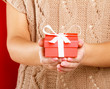 Photo: Female hand holding gift box isolated on red background Female hand holding gift box isolated on red background