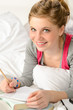 Smiling girl preparing for exams in bed