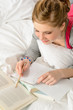 Teenage girl concentrating on studying in bed