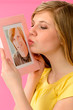 Young girl holding and kissing boyfriend's picture