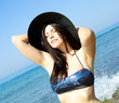 Happy model with hat in the water tanning with bikini
