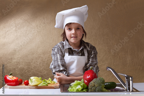 Photo: Little boy with chef hat washing vegetables Little boy with chef hat washing vegetables