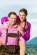 Paar in Tracht auf Wiese vor Bergpanorama