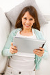 Young woman lying on the couch and working with a digital tablet