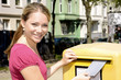 Photo: Junge Frau vor Briefkasten Junge Frau vor Briefkasten