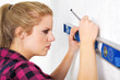 Junge Frau mit Wasserwaage zeichnet an Wand