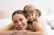 Daughter hugging her mother on the white bed