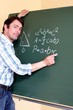 Lehrer schreibt auf Tafel Geometrieformel auf