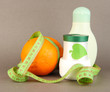 Orange with measuring tape and body cream, on color background