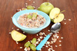 Useful oatmeal in bowl with fruit on wooden table close-up