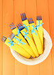 Foto: Blue plastic forks wrapped in yellow paper napkins, in basket, Blue plastic forks wrapped in yellow paper napkins, in basket,