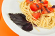 Spaghetti with tomatoes and basil leaves on wooden background