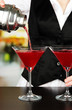 Barmen hand with shaker  pouring cocktail into glasses,