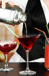 Barmen hand with shaker  pouring cocktail into glass,