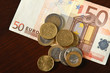 Photo: Money: euro coins and bills close up isolated on wood background Money: euro coins and bills close up isolated on wood background