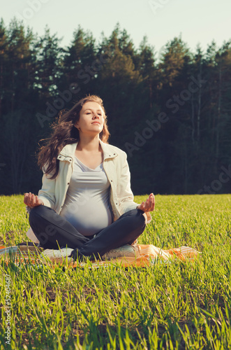 Photo: Beautiful pregnant woman relaxing on grass Beautiful pregnant woman relaxing on grass