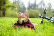 Barefoot cyclist on a halt reads lying in fresh green grass