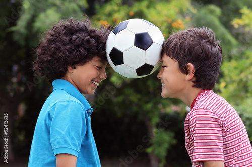Photo: Two young boys playng with a soccer ball - close view Two young boys playng with a soccer ball - close view
