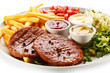 Foto: Grilled steaks, French fries and vegetables Grilled steaks, French fries and vegetables