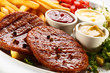 Foto: Grilled steaks, French fries and vegetables Grilled steaks, French fries and vegetables