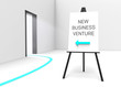 Easel with sign "New business venture" Arrow pointing at doorway