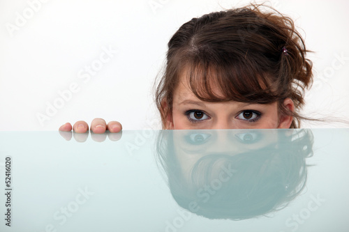 Photo: woman hiding behind a glass table woman hiding behind a glass table