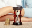 Female hand's with hourglass and coin