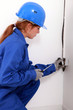 Young female trades apprentice wiring a power point