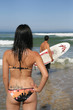 Woman watching a man with a surfboard