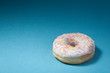 Photo: donut with white icing isolated on blue background with copyspac donut with white icing isolated on blue background with copyspac