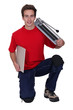 young handyman posing with a tile cutter and a tile
