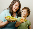 fat woman holding salad and little cute boy with hamburger