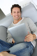 Adult man laying on sofa with tablet