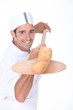 Baker pulling a freshly baked baguette out from the oven