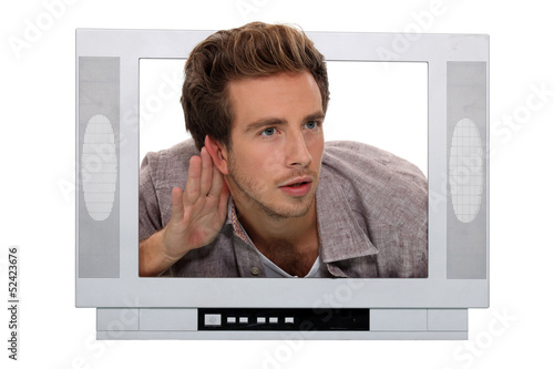 Photo: young man through a TV screen listening something carefully young man through a TV screen listening something carefully