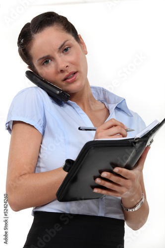 Photo: Receptionist on the telephone and writing in agenda Receptionist on the telephone and writing in agenda