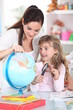 Photo: Mother and daughter looking at a globe with a magnifying glass Mother and daughter looking at a globe with a magnifying glass