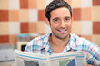 Man reading a newspaper in the kitchen