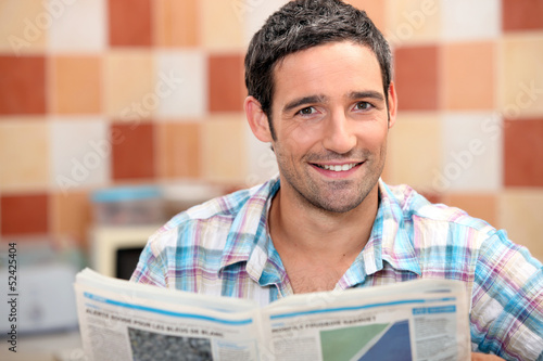 Photo: Man reading a newspaper in the kitchen Man reading a newspaper in the kitchen
