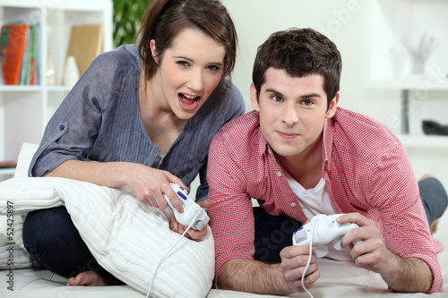 Photo: Couple of teenagers playing video games. Couple of teenagers playing video games.