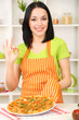 Girl housewife with delicious pizza on kitchen background